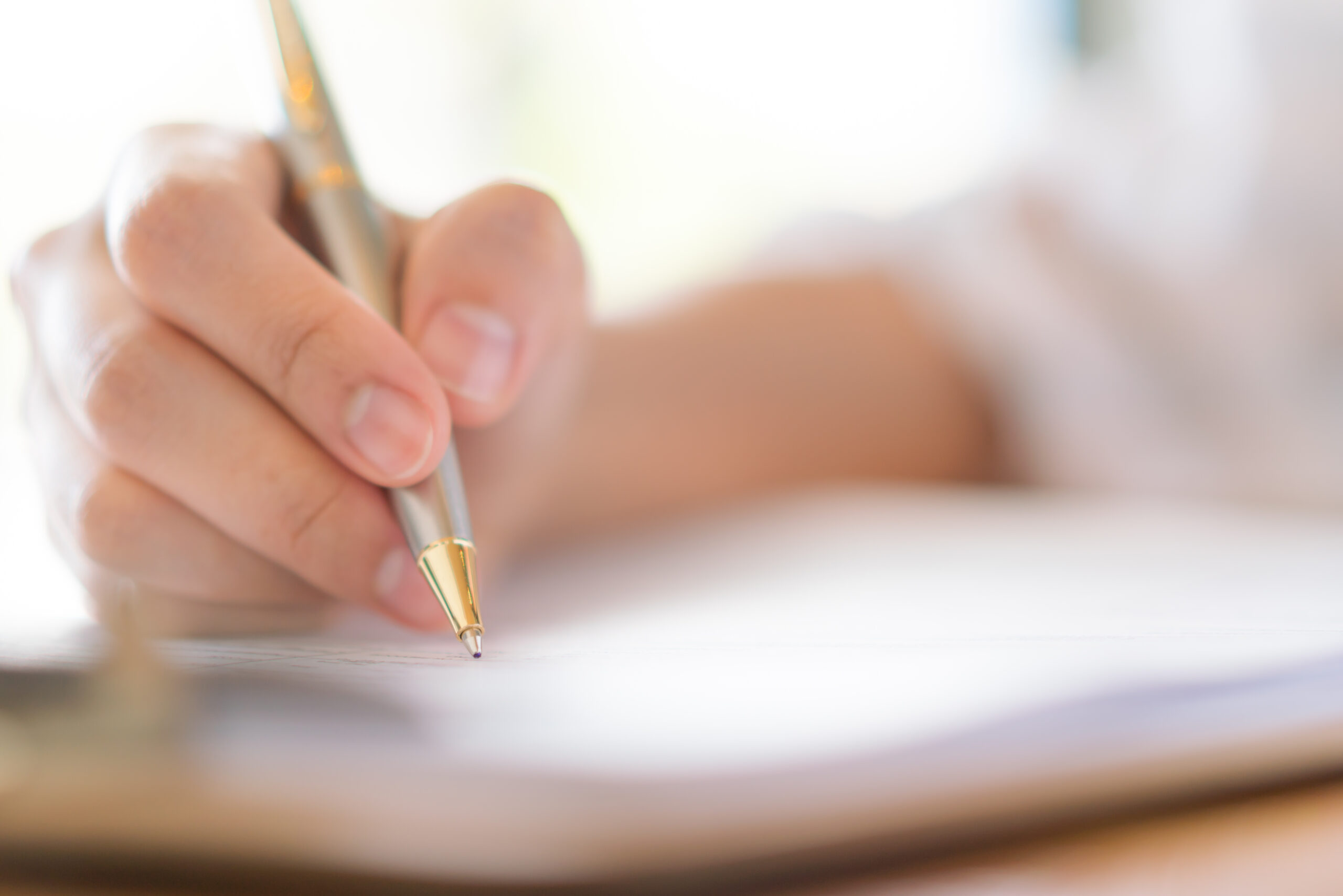 Hand with pen over application form .